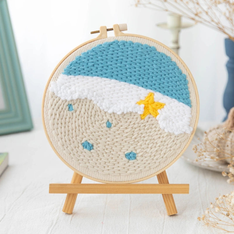 Handmade ocean beach punch needle hoop art with blue waves, sand, and a yellow starfish.