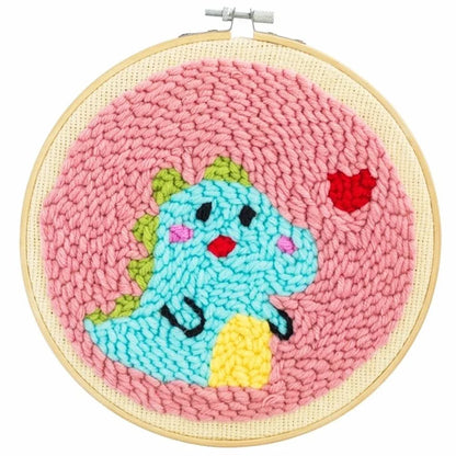 Handmade punch needle hoop art featuring a cute blue dinosaur on a pink background.