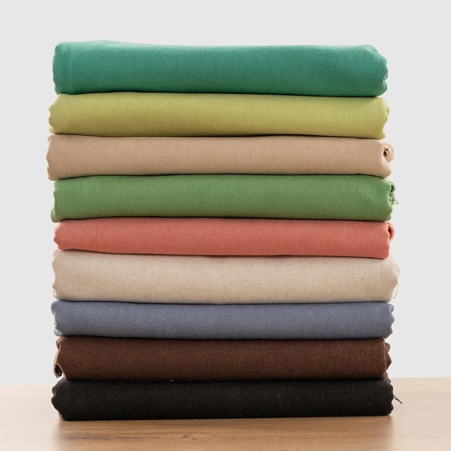 Stack of colorful cotton linen embroidery fabric swatches in various earth tones.