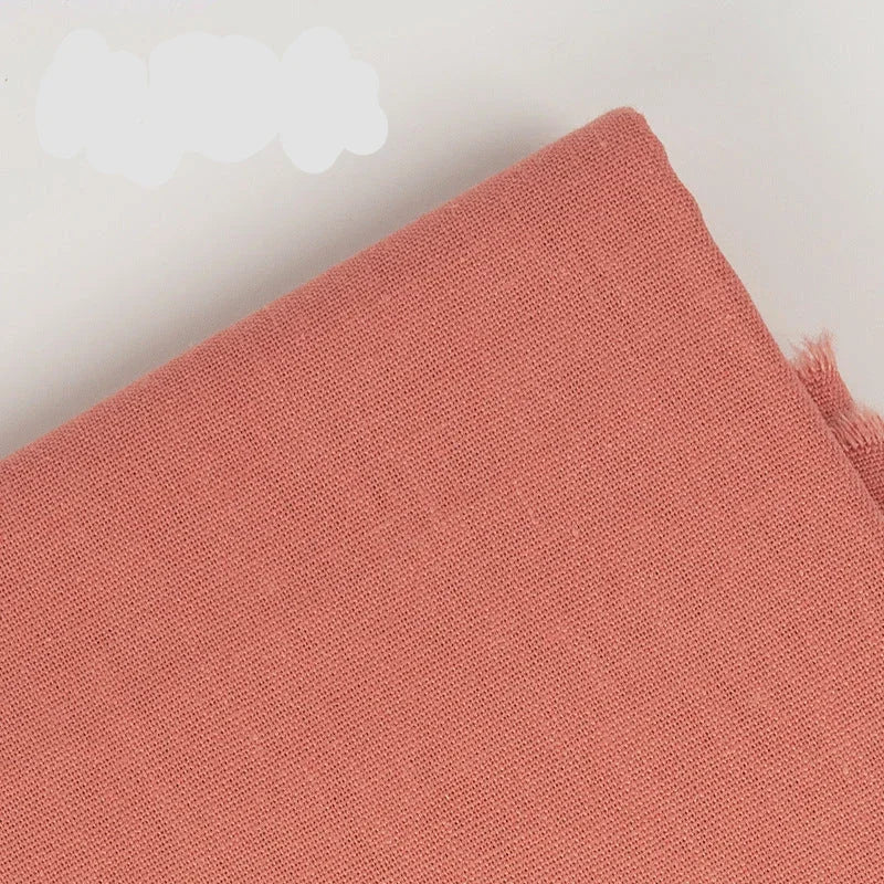 Close-up of salmon pink cotton linen embroidery fabric texture.