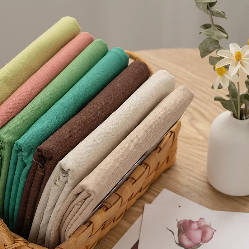 Assorted colorful cotton linen embroidery fabric rolls in a woven basket.