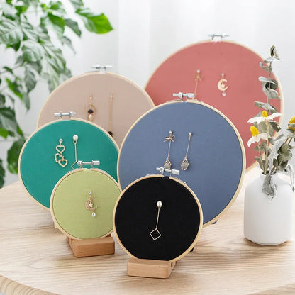 Assorted colorful embroidery hoop jewelry organizers displaying earrings and necklaces.