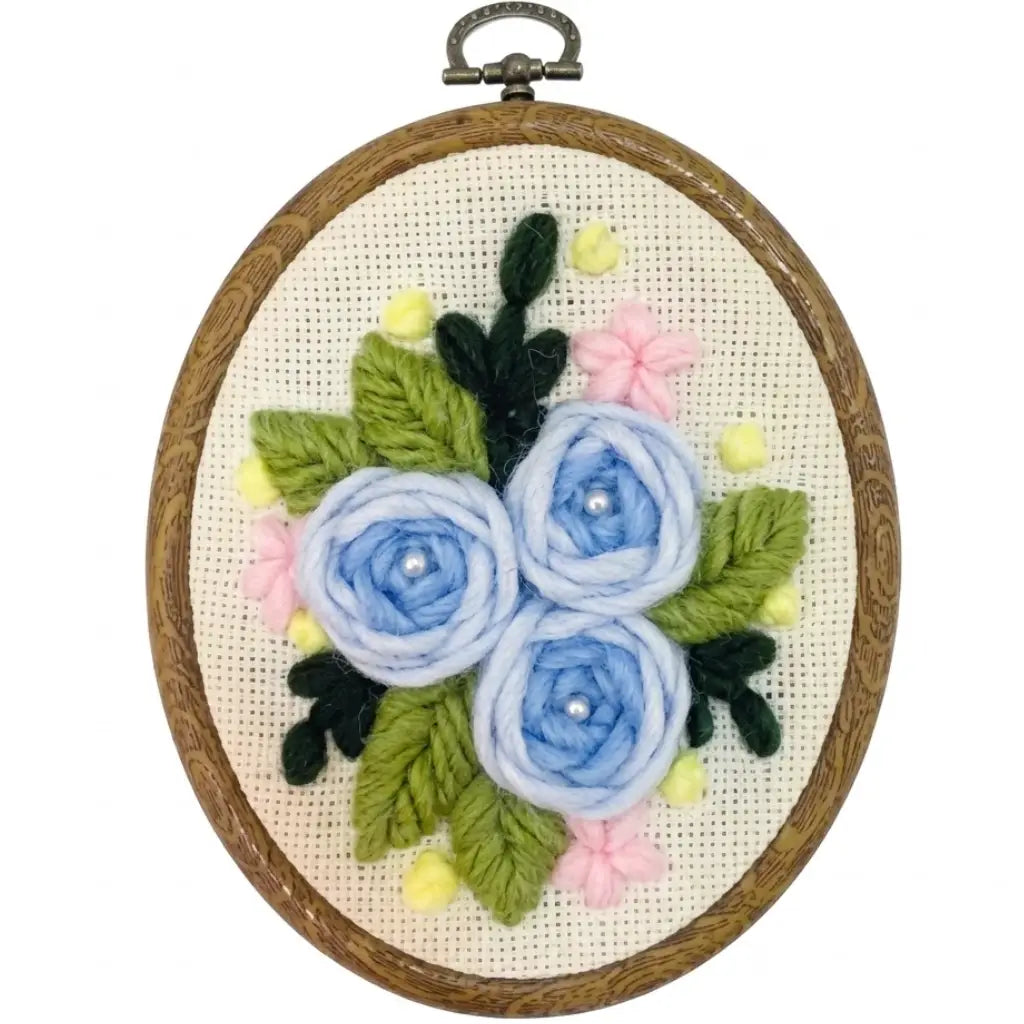 Blue flower punch needle embroidery kit with pink blossoms in a wooden hoop.