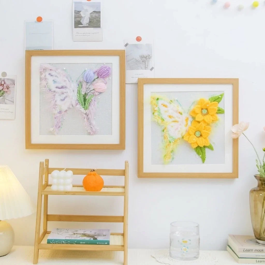 Two Calivra Craft butterfly DIY embroidery kits in wooden frames displayed on a wall.