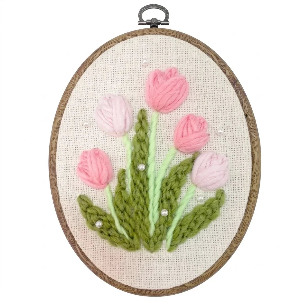 Pink tulip punch needle embroidery kit with green leaves in a wooden hoop by Calivra Craft.