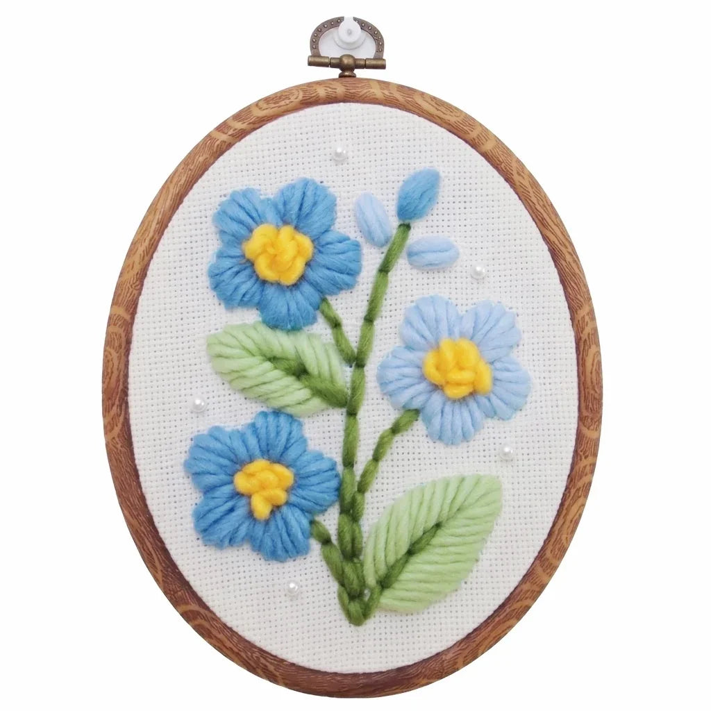 Blue flower punch needle embroidery kit with yellow centers in a wooden hoop.