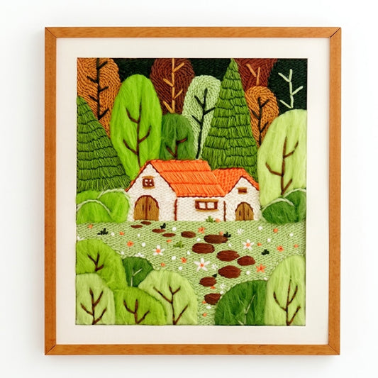 Embroidered landscape featuring a cozy cottage with a red roof surrounded by green and brown trees.