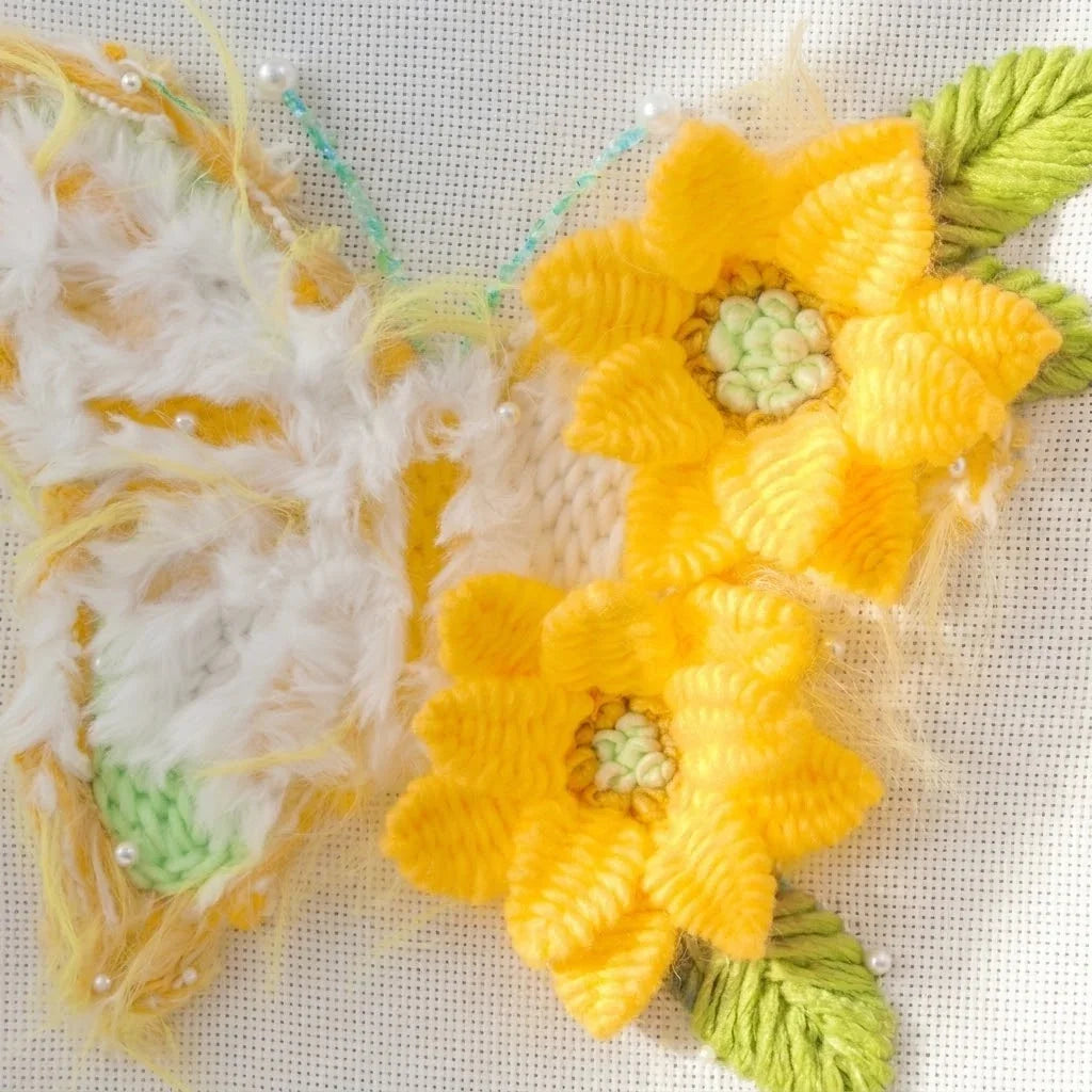 Yellow and white textured butterfly embroidery with yellow flowers and green leaves.