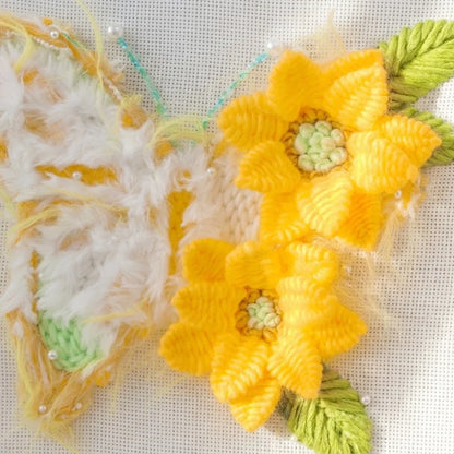 Yellow and white textured butterfly embroidery with yellow flowers and green leaves.