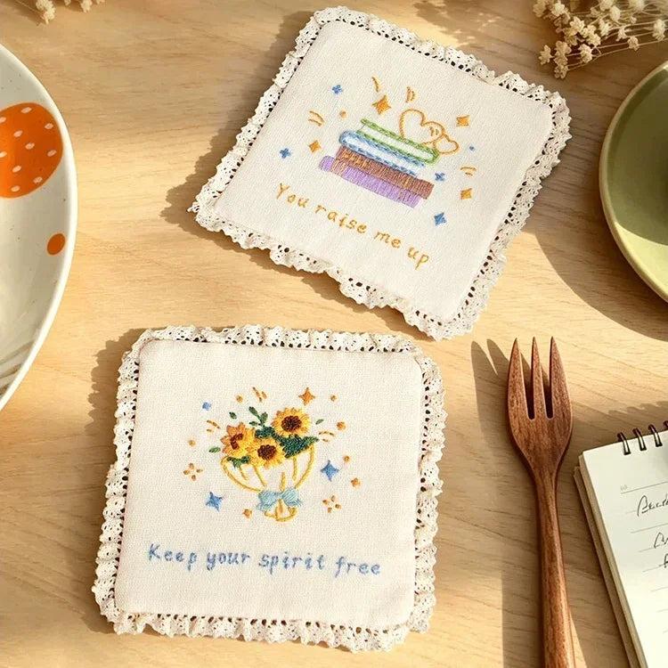 Two white lace-edged coasters with colorful cross-stitch embroidery and quotes.