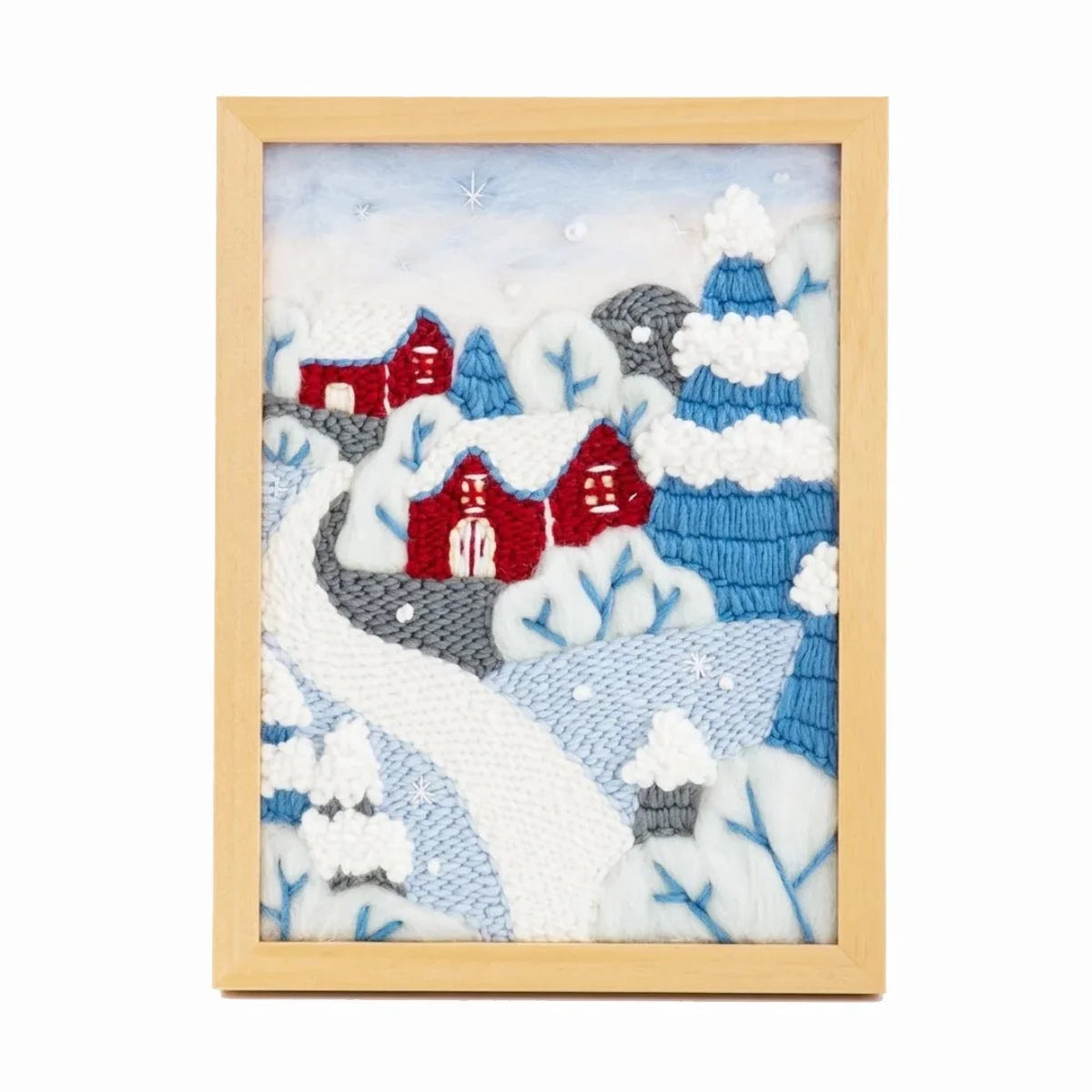 A framed needle felt landscape art piece featuring red houses and snowy trees.