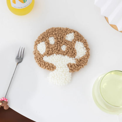 Mushroom-shaped cookie with brown and white icing on a white surface with a fork and container.