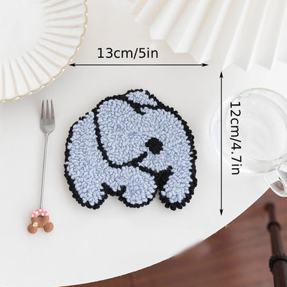 Small rug with a dog design on a table, showing dimensions and placed next to a fork and glass.