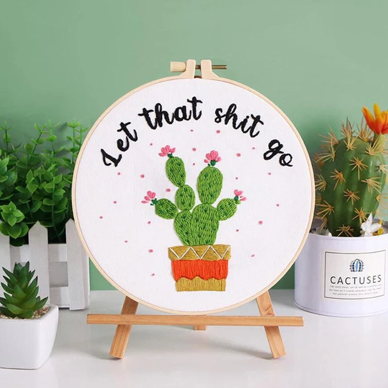 A playful and empowering embroidery design featuring a cute green cactus in a colorful pot with blooming pink flowers. The bold stitched quote “Let That Sh*t Go” adds humor and positivity — a reminder to relax, let go, and enjoy the moment. Perfect for modern home décor or as a fun handmade gift for friends who love a good laugh and creative vibes.