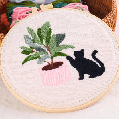 Embroidery hoop with a black cat and potted plant design.