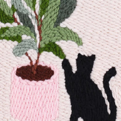 Embroidered design of a black cat and a potted plant on a textured fabric background