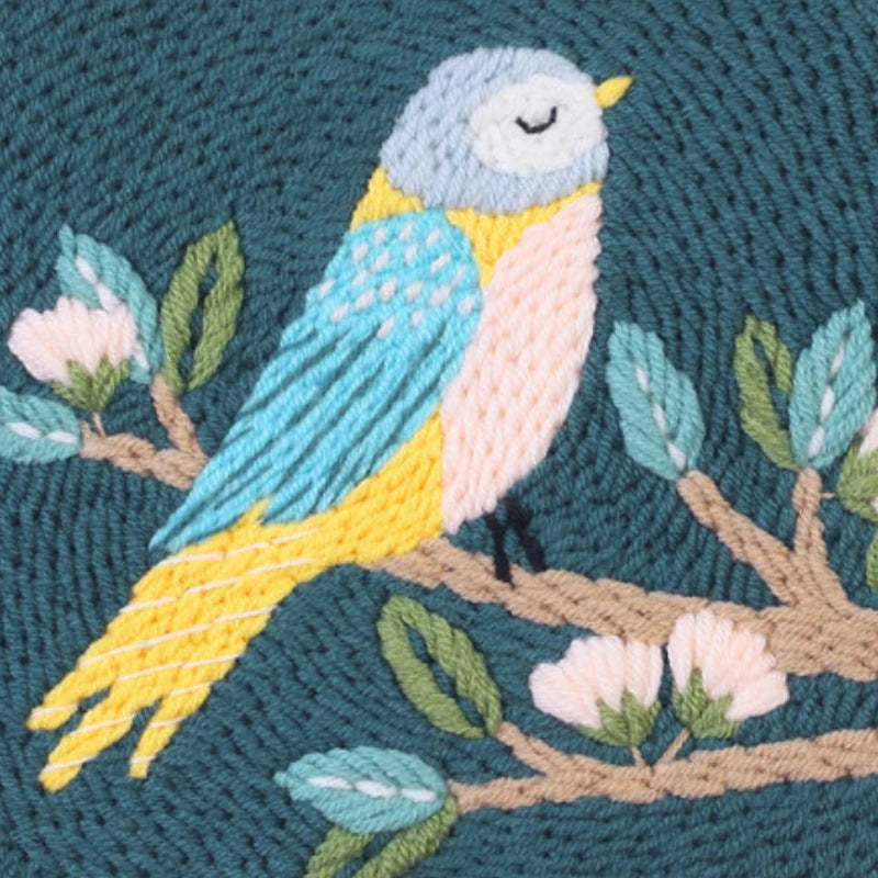 Embroidered bird on a branch with flowers on a teal background