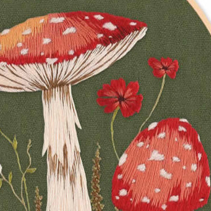 Embroidery of red mushrooms with white spots on a green background