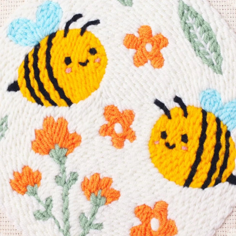 Embroidered design of two bees and flowers on a white background