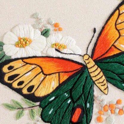 Embroidered butterfly design on fabric with flowers and leaves