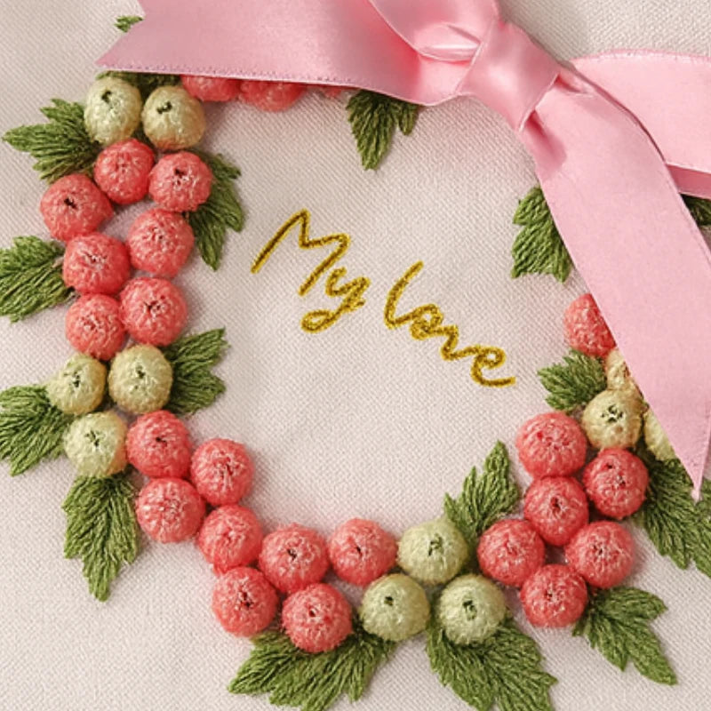 Embroidered wreath with berries and leaves and a pink ribbon, with 'My love' embroidered in gold.