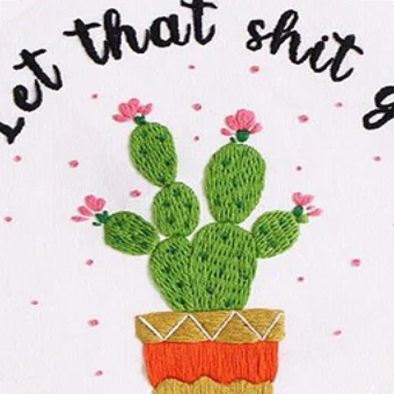 This embroidery design features a lively green cactus with delicate pink blossoms on each pad, planted in a colorful pot with golden and orange details. The playful pink dots scattered around add a fun touch, while the hand-stitched phrase  gives it a humorous and carefree vibe — perfect for modern home decor with personality.