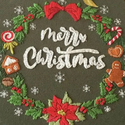 This embroidery design features a charming Christmas wreath encircling the words “Merry Christmas” stitched in elegant white script. The wreath is adorned with red bows, holly leaves, berries, a gingerbread man, candy canes, and a poinsettia flower, all brought to life with festive colors. The deep green background enhances the bright reds and whites, creating a warm, joyful holiday atmosphere — perfect for Christmas decoration or as a heartfelt handmade gift.