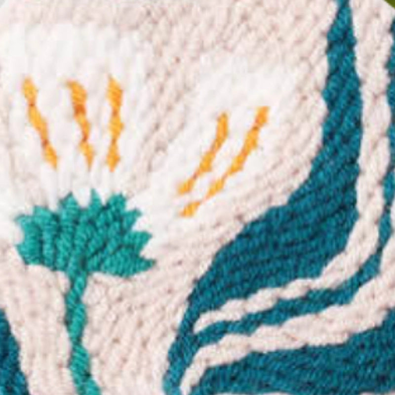 Close-up of embroidered fabric with teal, orange, and white patterns