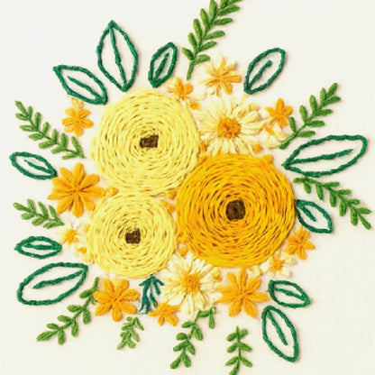 Embroidered design of yellow flowers and green leaves on a white background
