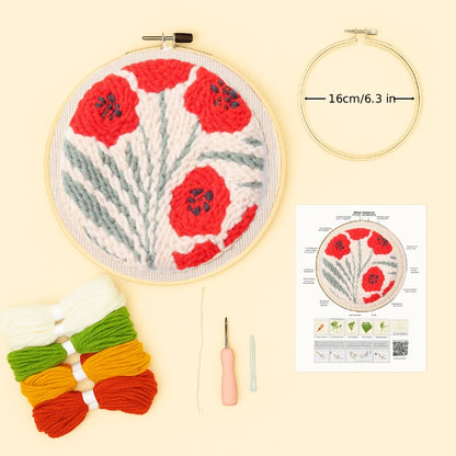 Embroidery hoop with red floral design, yarn, needle, and instruction sheet on a beige background