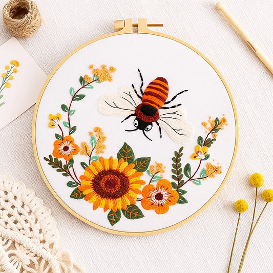 Embroidery hoop with a bee and floral design on a white background
