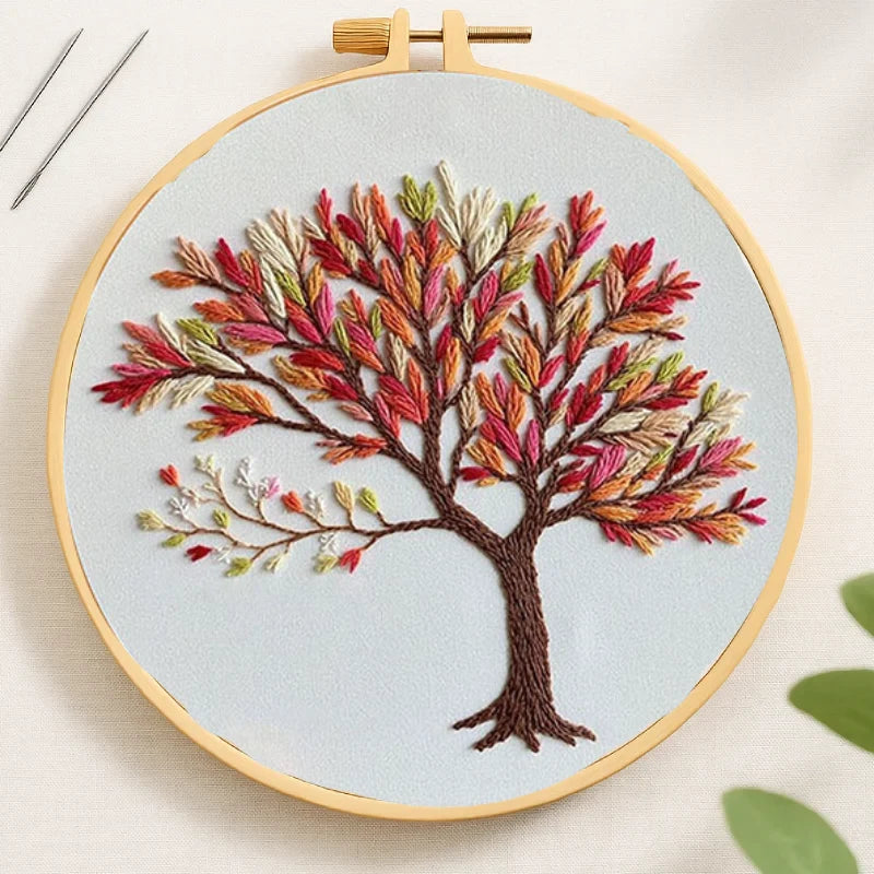 Embroidery hoop with a colorful tree design on light blue fabric.