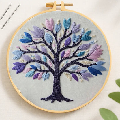 Embroidery hoop with a colorful tree design on a light background