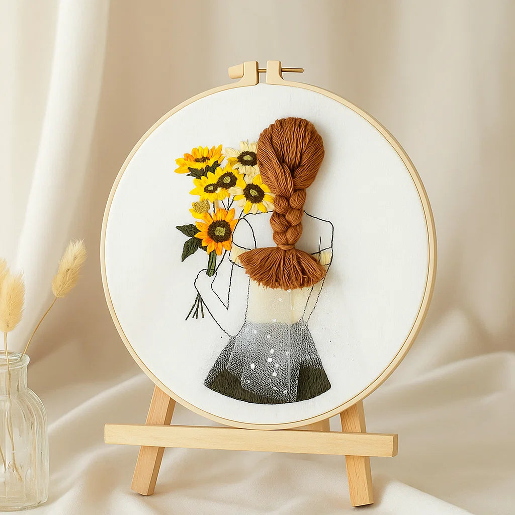 Embroidery hoop with a design of a woman holding sunflowers and braided hair, on a beige background.