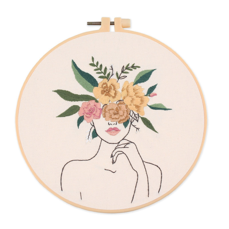 Embroidery hoop with a floral design of a woman's face on a white background