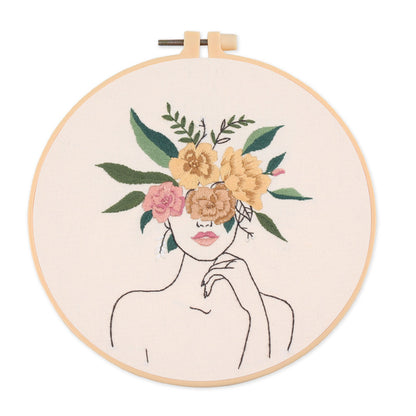 Embroidery hoop with a floral design of a woman's face on a white background