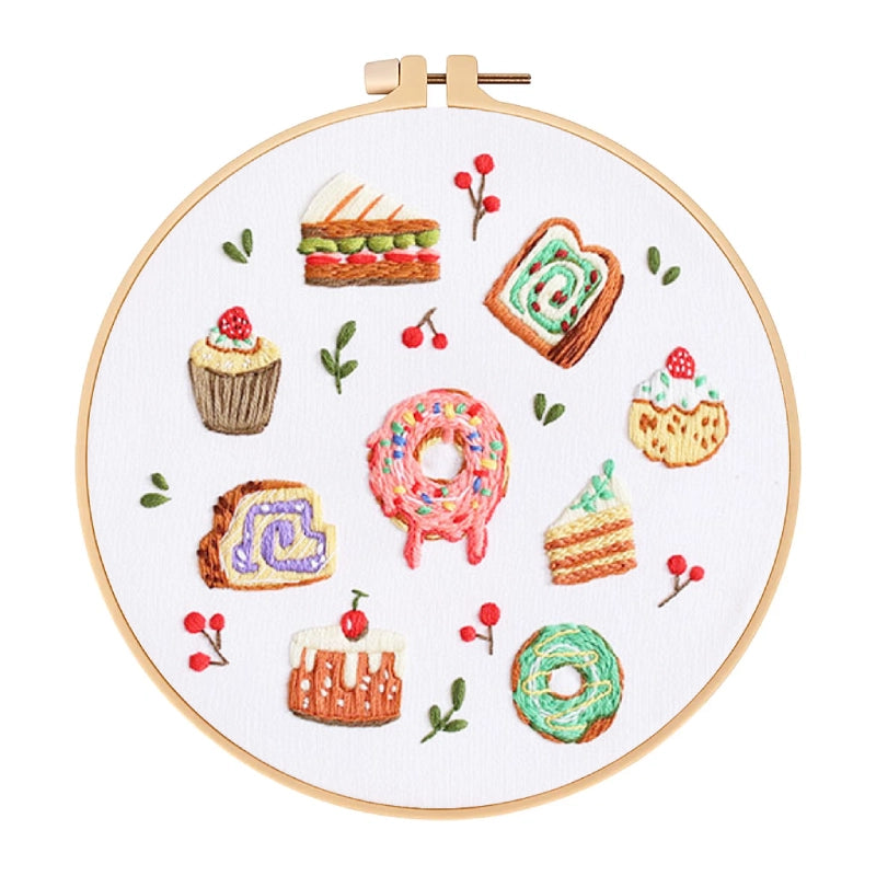 Embroidery hoop with colorful embroidered illustrations of desserts on a white background