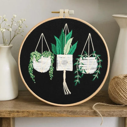 Embroidery hoop with plant-themed design on a wooden shelf.