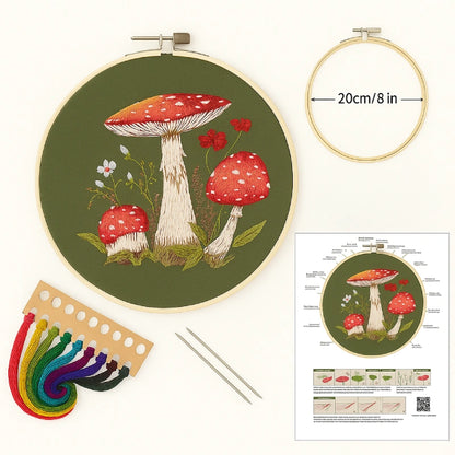 Embroidery hoop with mushroom design, embroidery floss, needles, and instruction sheet on a white background