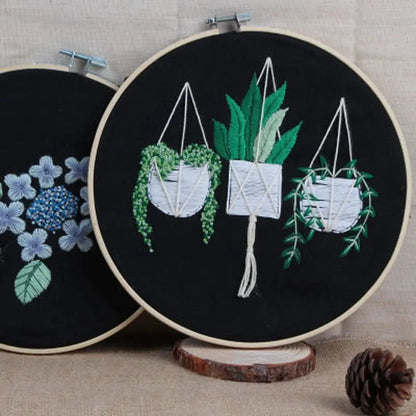 Embroidery hoops with plant designs on a wooden stand.