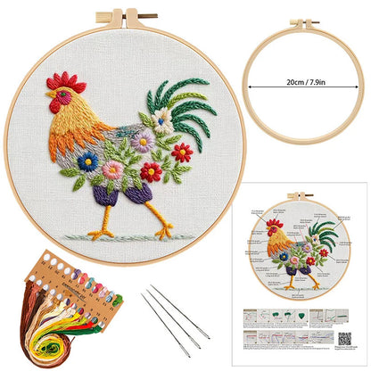 Embroidery kit with rooster design, hoop, threads, needles, and pattern guide on a white background.
