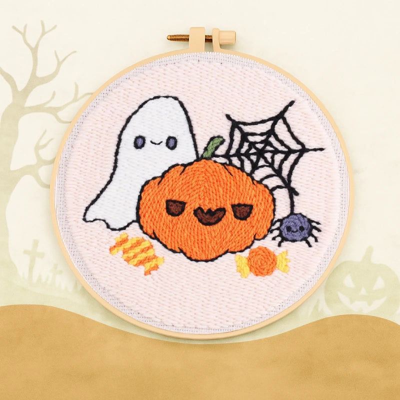 This punch needle design features a smiling pumpkin and a cute ghost surrounded by candies, a spider web, and a tiny spider.