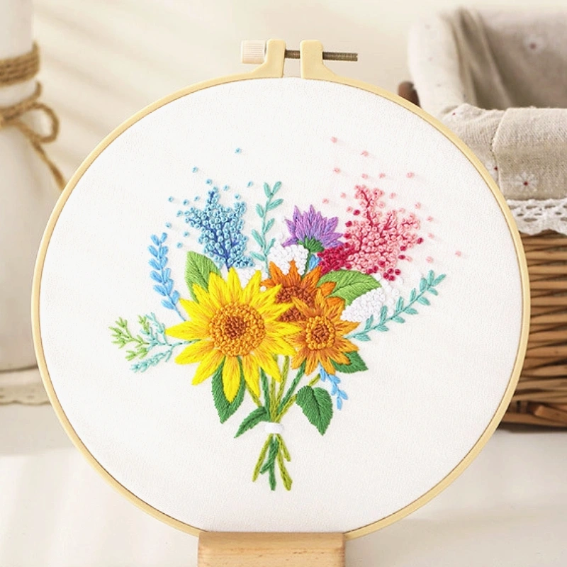 The Golden Bloom embroidery design captures the radiant charm of summer.
Set against a soft white fabric, two bright sunflowers stand proudly at the centre, symbolising warmth and optimism.
They are surrounded by delicate lavender, baby’s breath, and violet blossoms, creating a soft blend of pastel hues.
Gentle green leaves frame the bouquet, giving it a fresh and lively look — like a handful of sunshine gathered from a blooming summer garden.