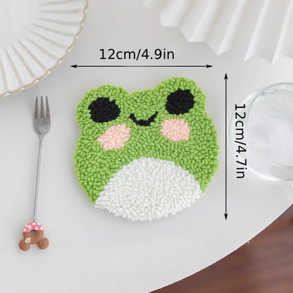 Green frog-shaped coaster with measurements on a white surface