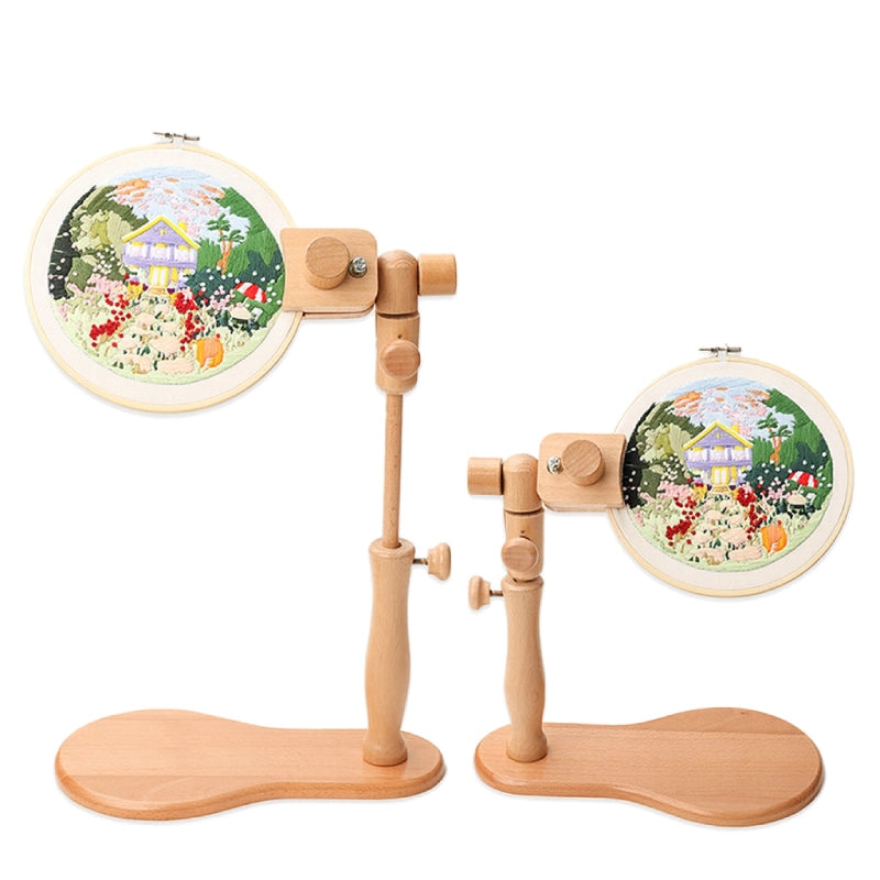 Wooden embroidery hoop stand with two hoops displaying embroidered scenes on a white background