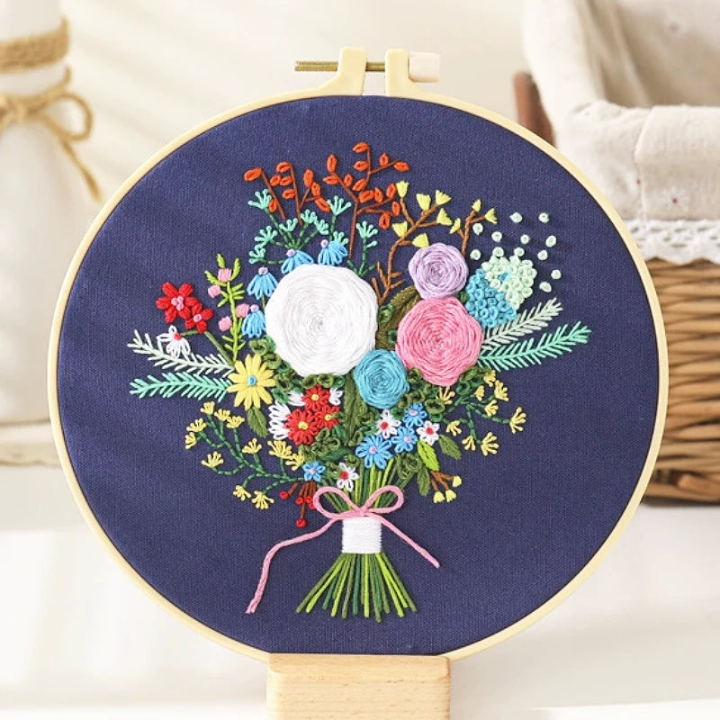 The Midnight Garden Bouquet features a stunning arrangement of hand-embroidered flowers on a deep navy background — elegant and serene like a quiet night sky.
At its heart bloom white roses of purity and hope, surrounded by pink and lavender blossoms that add a touch of romance.
Tiny red and blue flowers bring playful brightness, while a delicate pink bow ties the bouquet together, adding a soft, graceful charm.
It’s a perfect balance of colour, texture, and emotion — like capturing the calm beauty of a mid