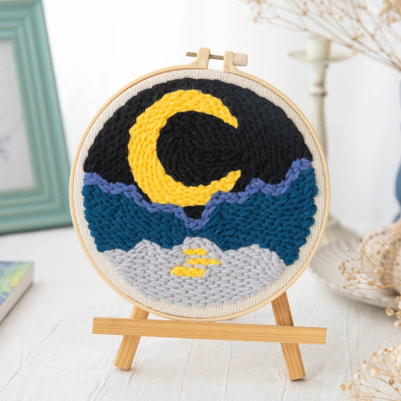 Embroidery hoop with a moon and mountain design on a white surface
