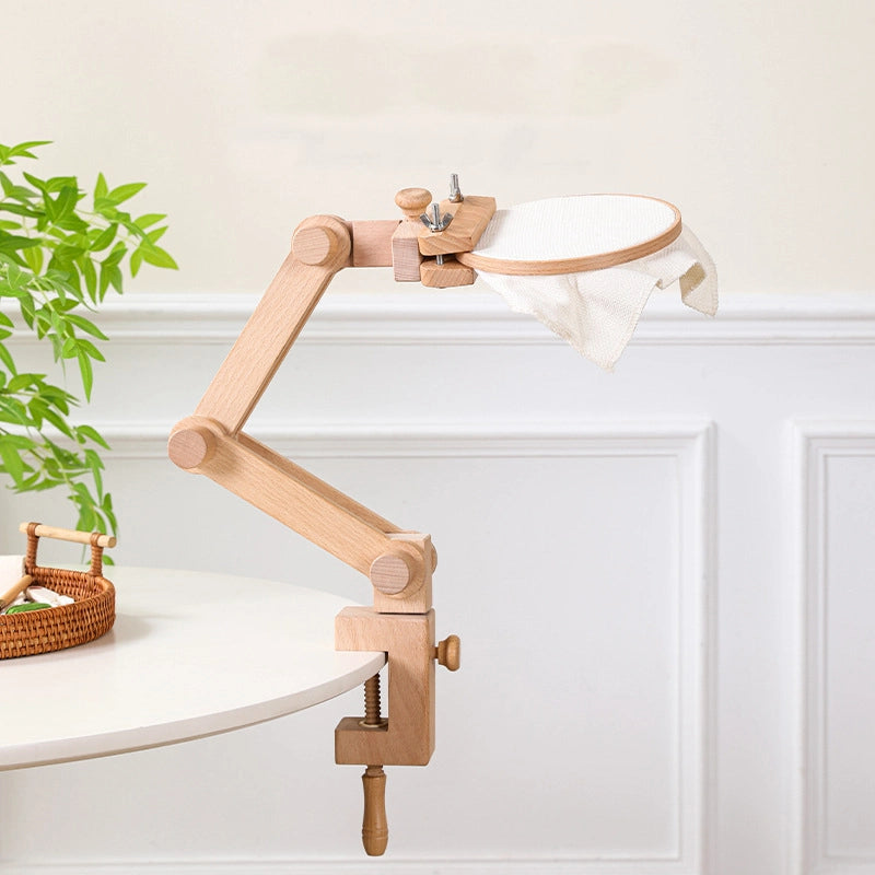 Wooden clamp lamp with white shade on a white surface with a plant in the background