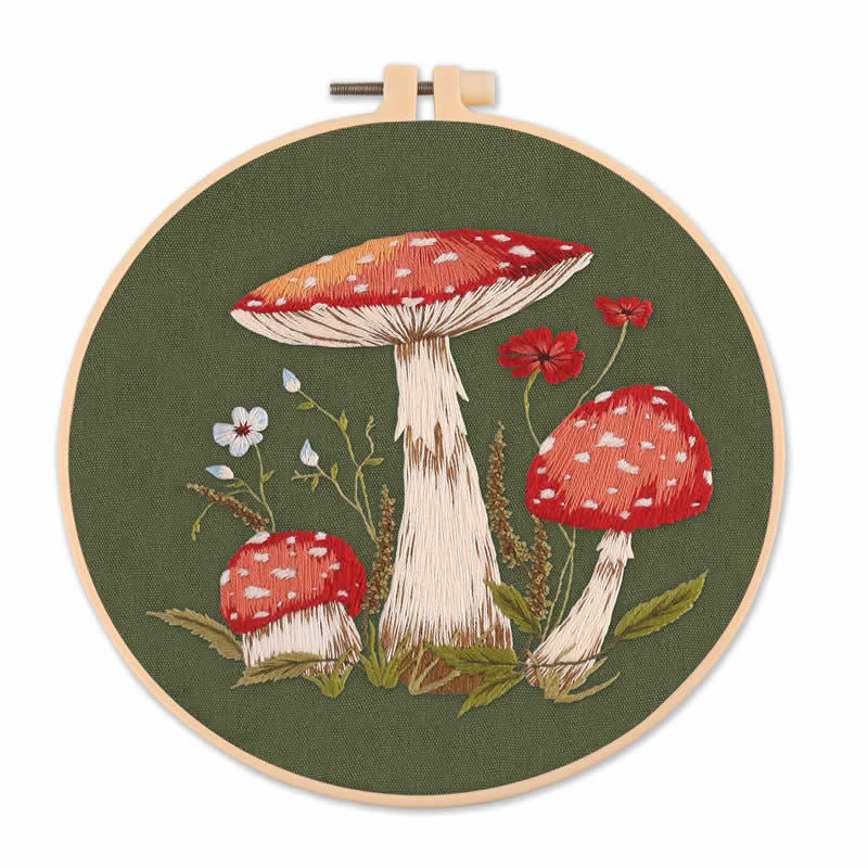 Embroidery hoop with red and white mushrooms and flowers on green fabric