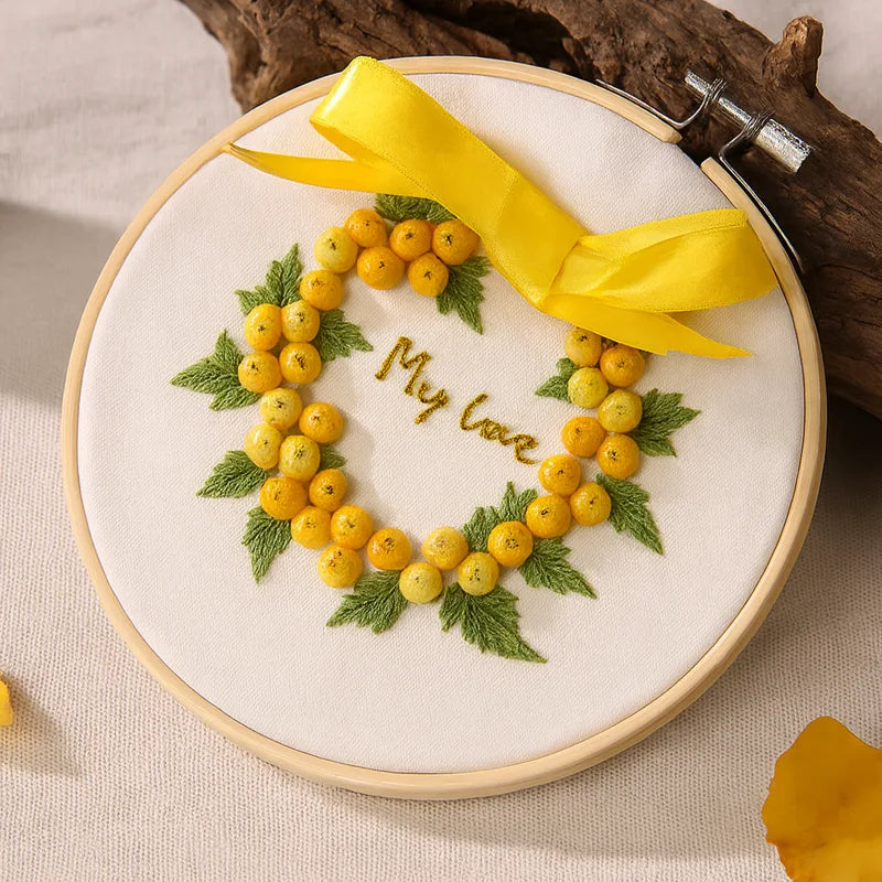 Bright, cheerful, and full of warmth — the Sunshine Wreath design captures the glow of happiness in every stitch.
Golden yellow berries and fresh green leaves form a radiant heart-shaped wreath, tied with a satin yellow bow. It’s a joyful symbol of love and optimism, perfect for brightening your home or gifting to someone dear.